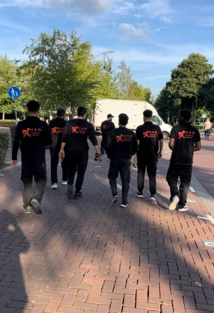 Het KADI-team loopt in bedrijfskleding naar de verhuiswagen