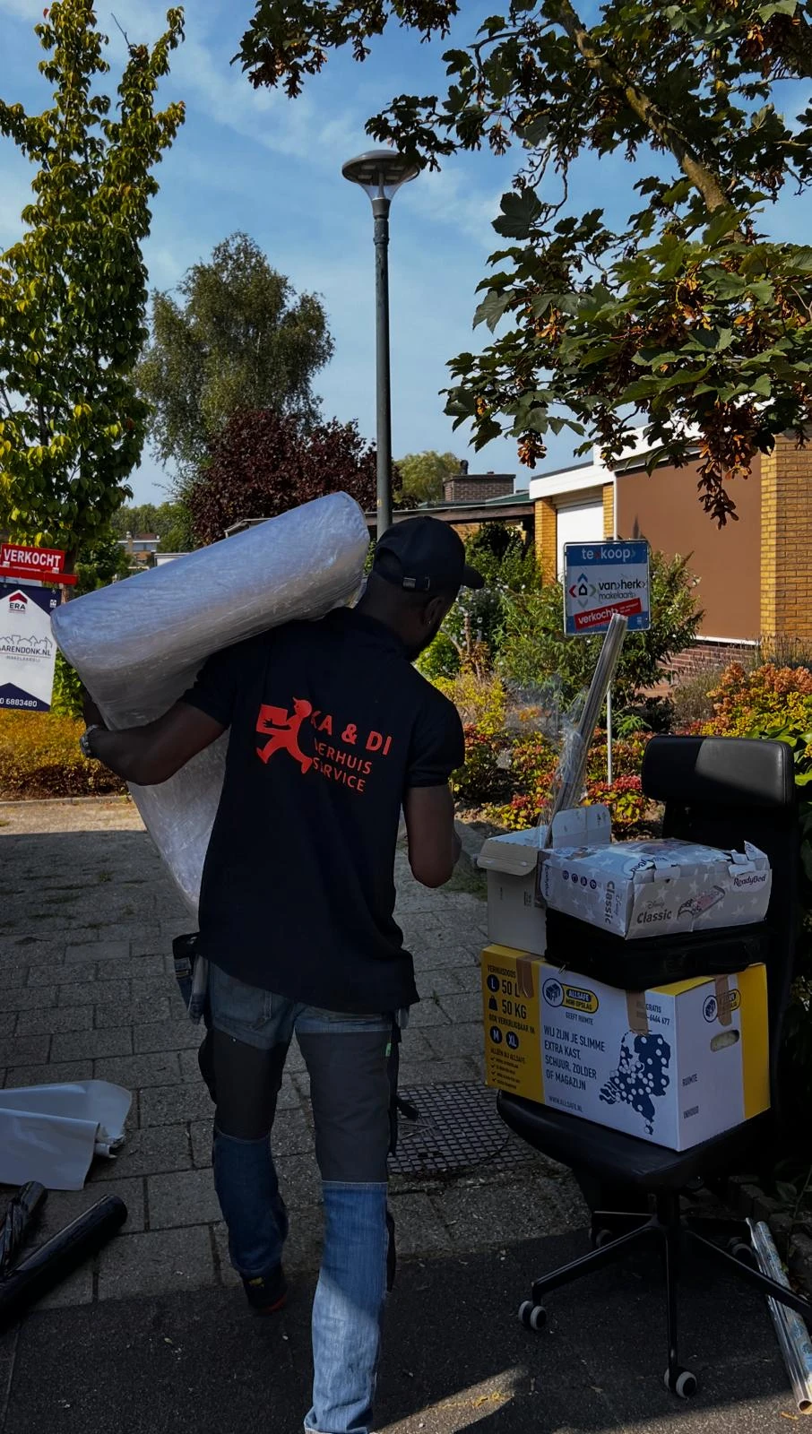 KADI-verhuizer draagt een ingepakt meubel bij een woning